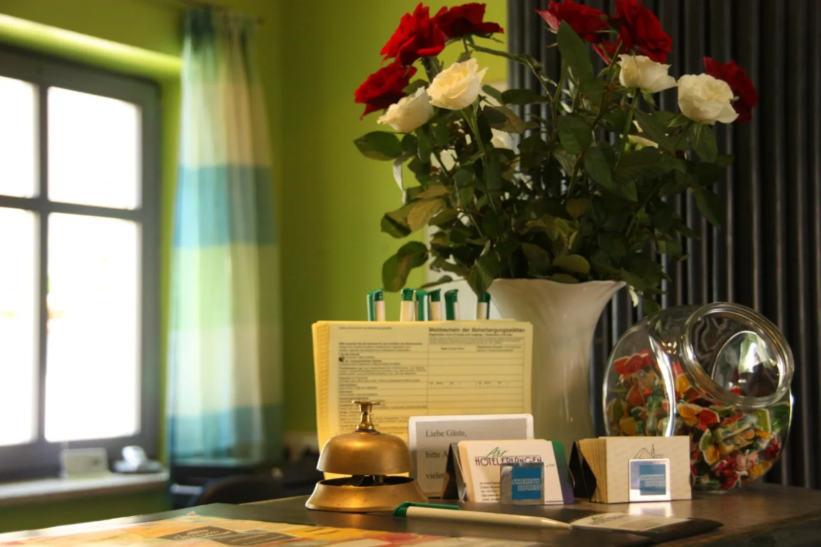 Rezeption des Art-Hotels Erlangen mit Empfangsglocke und Blumen